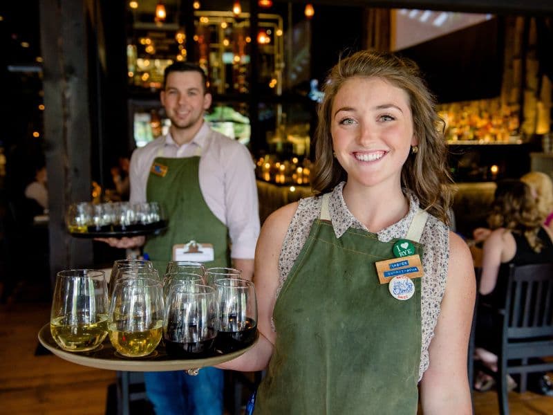 Two food & beverage servers holding trays of drinks. Photo courtesy of BHC.