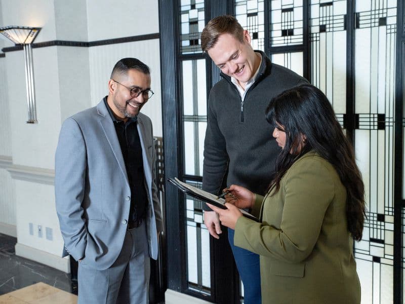 Hotel account executive discussing paperwork with two guests. Photo credit BLLHA and Accor Hotels & Resorts